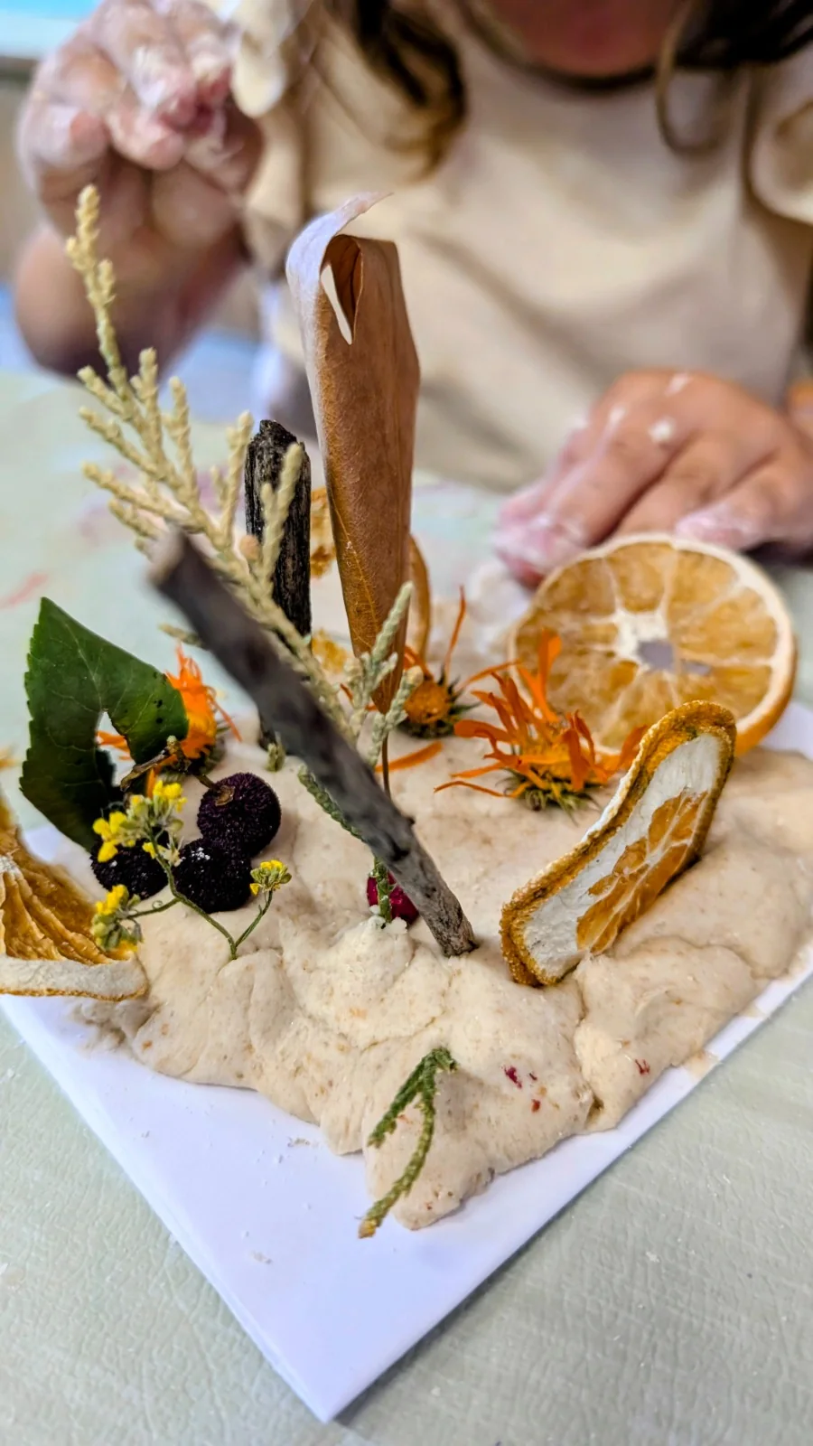 Escultura de arte con masa, flores secas y naranjas